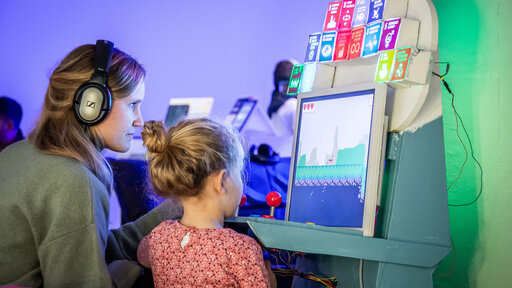 Eine Frau und ein Kind stehen vor einem Computer und spielen ein Computerspiel